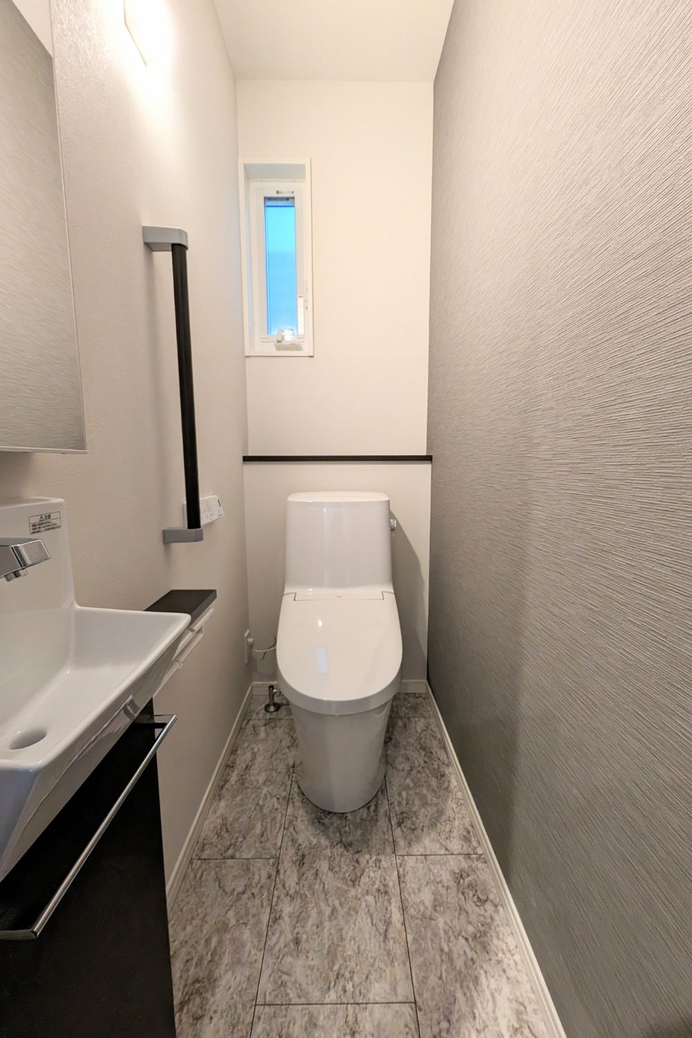 T-1／シックな雰囲気にまとめたトイレは独立洗面付きで収納にも困らない便利な設計。
