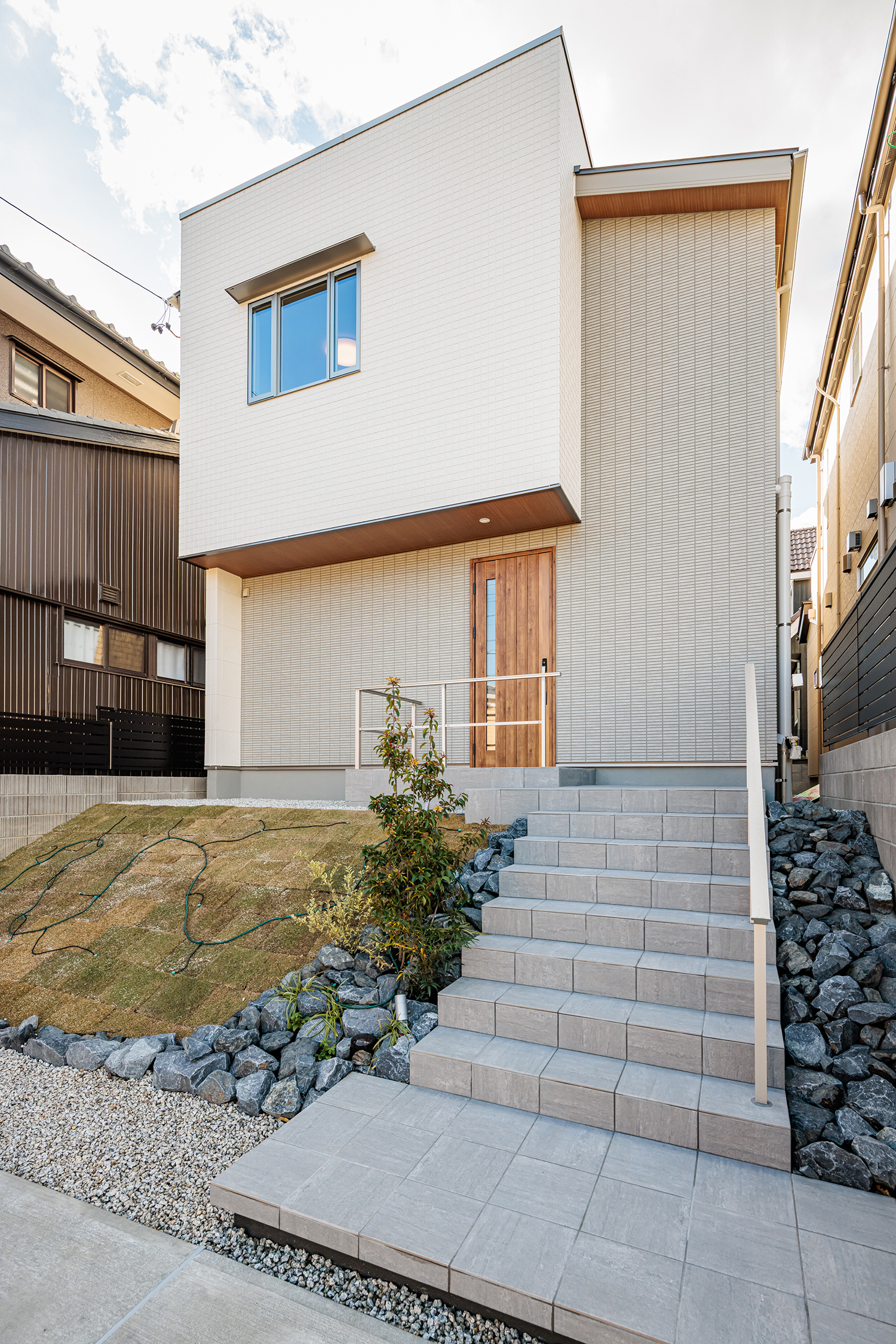 T-2／玄関へと続くアプローチは、タイル張りの階段に芝と植栽の緑を配した、清々しく開放的なデザイン。