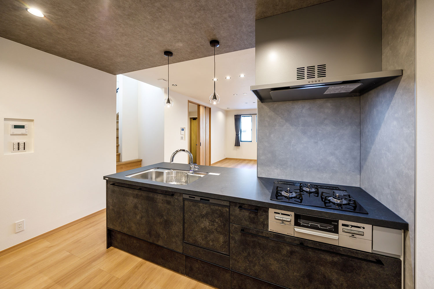 T2／チャコールカラーのキッチンは対面フラットタイプにすることで開放感を損なうことなく空間のアクセントに。