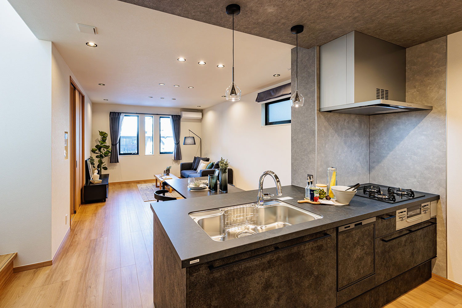 T2/チャコールカラーのキッチンは対面フラットタイプにすることで開放感を損なうことなく空間のアクセントに。